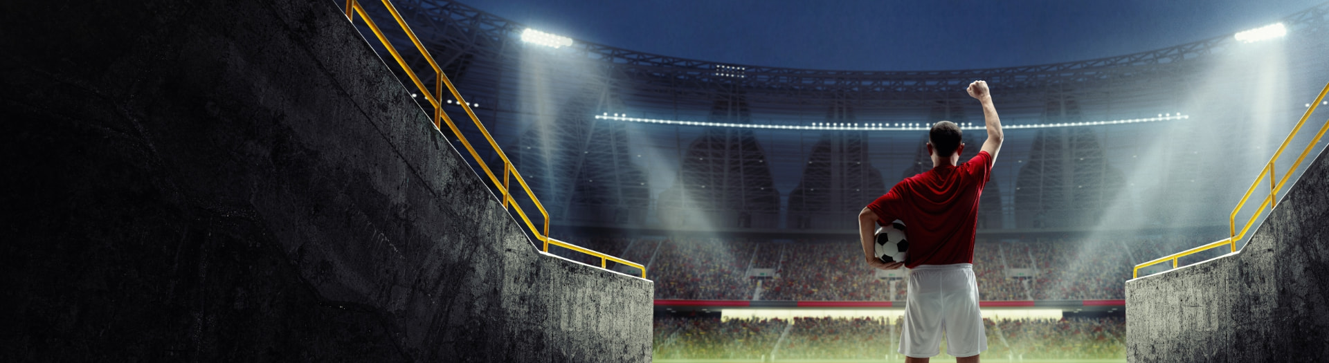 Fußballspieler mit Ball im Flutlicht-Stadion